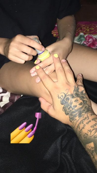 Novio planea noche de chicas con su novia; mujer pintándole las uñas a su novio