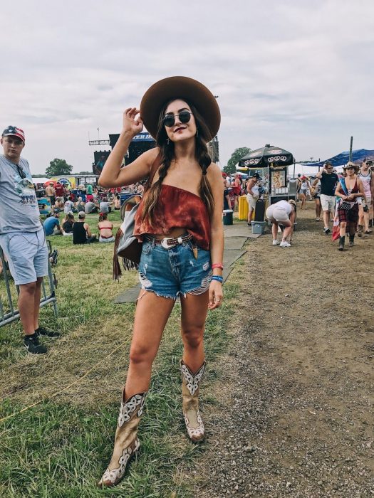 Chica usando un outfit de blusa roja, shorts y botas vaqueras 