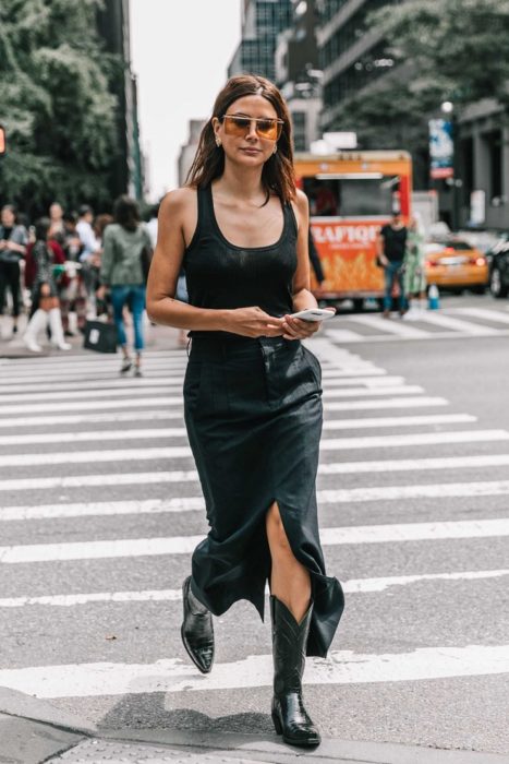 Chica usando un vestido negro con botas vaqueras 