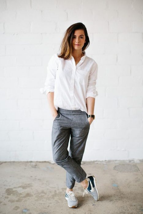 Chica usando pantalones de vestir color gris, blusa blanca y tenis de color verde 