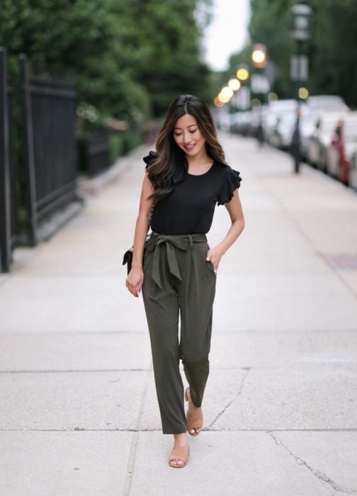 Chica usando un pantalón verde miliar, blusa negra y sandalias de tacón cuadrado bajas 