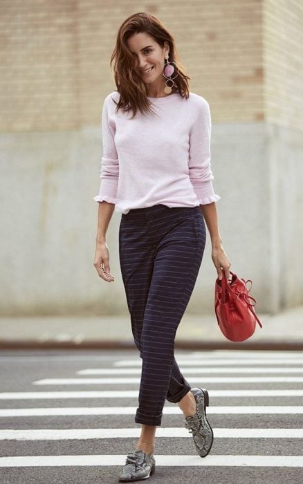 Chica caminando por la calle mientras usa una blusa rosa, pantalon de color morado con estampado de cuadros y zapatos animal print de color gris 