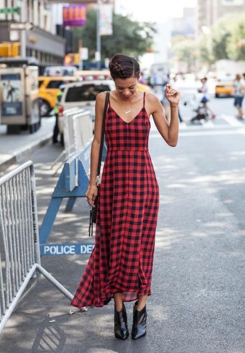 Chica usando un vestido de color rojo con cuadros negros y botines 