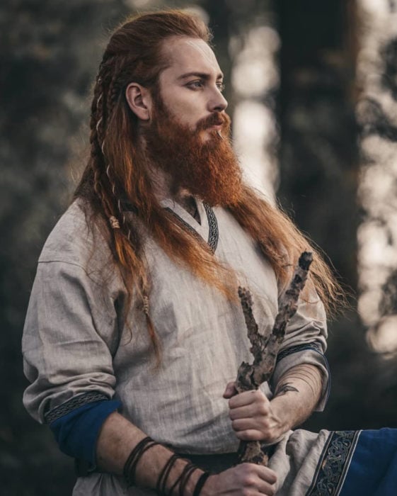 Hombre pelirrojo de cabello largo y con peinado de trenzas, de aspecto vikingo, con barba y bigotes tupidos