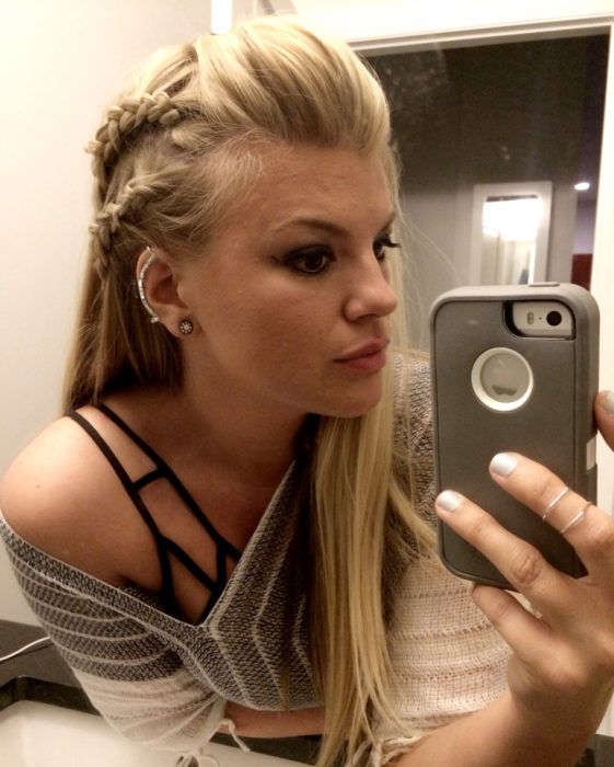 Chica rubia con peinado vikingo de trenzas, tomándose selfie frente al espejo