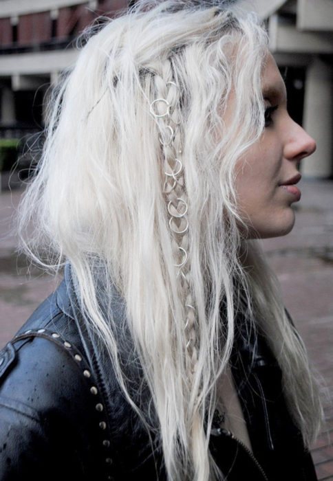 Chica de cabello blanco despeinado, con trenza adornada con argollas