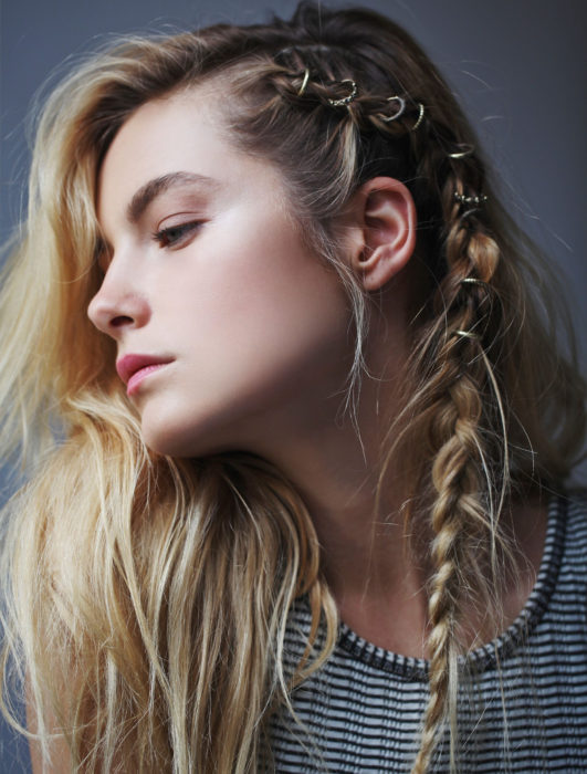 Chica rubia con cabello suelto y con una trenza de lado peinada con argollas al estilo vikingo