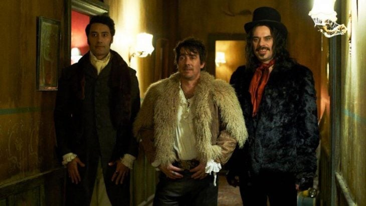 Grupo de hombres con aspecto vampiresco en el pasillo de un hotel. escena de la película What We Do in the Shadows