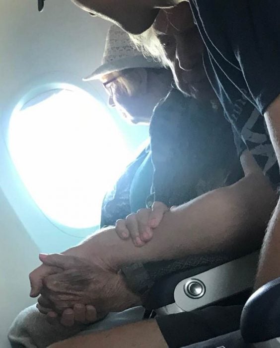 Chico sosteniendo la mano de una abuelita de 96 años en pleno vuelo