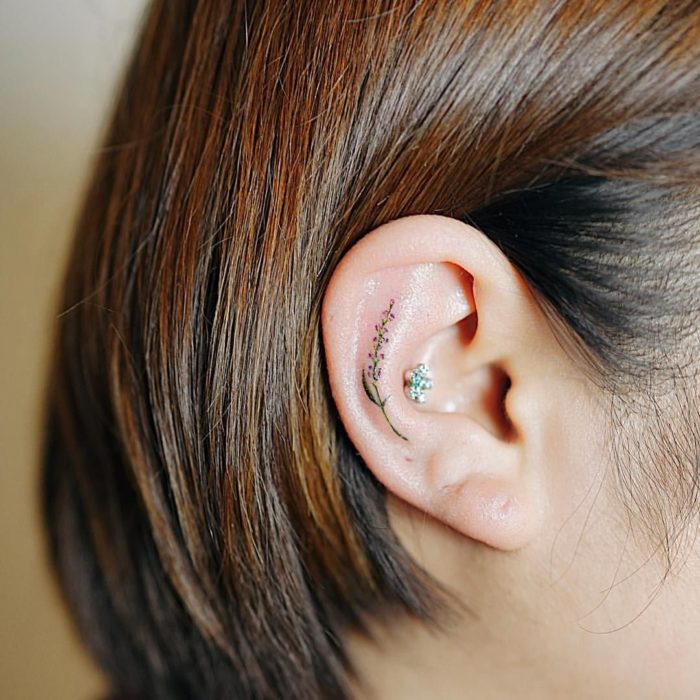 Chica con un tatuaje en la oreja en forma de flores de colores 