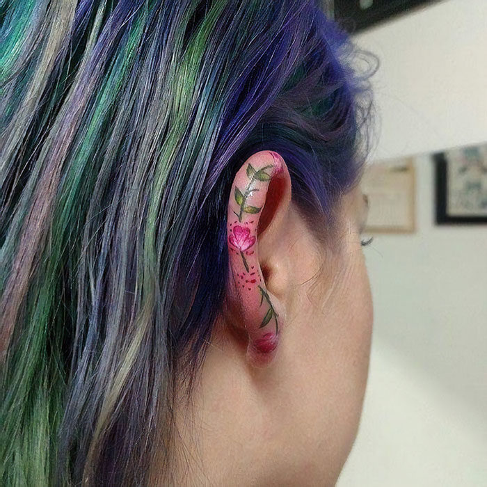 Chica con un tatuaje en la oreja en forma de flores de colores 