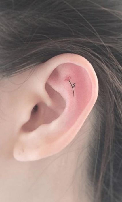 Chica con un tatuaje en la oreja en forma de flores de colores 