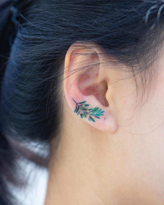 Chica con un tatuaje en la oreja en forma de flores de colores 