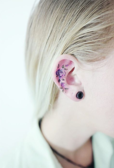 Chica con un tatuaje en la oreja en forma de flores de colores 