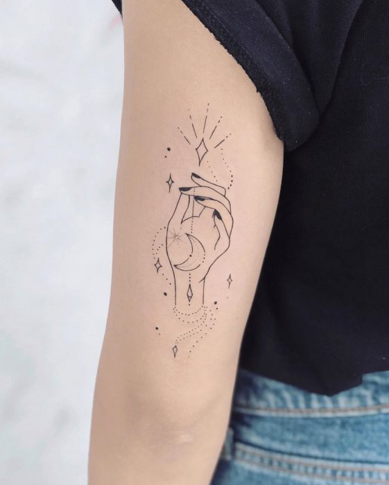 Tatuaje con una mano sosteniendo a la luna por un hilo delgado inspirado en Hocus Pocus