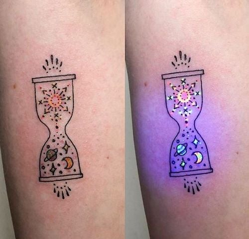 Tatuaje con silueta de reloj de arena y planetas dentro de él con efecto ultravioleta
