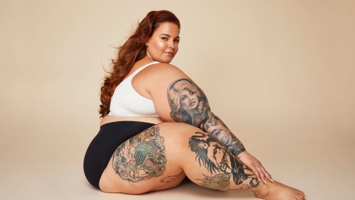 Tess Holliday fa la modella con pantaloncini neri, camicetta bianca e mostra i suoi tatuaggi