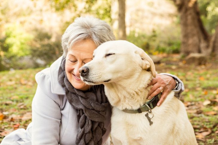 Mujer adulta mayor abrazando amorosamente a su perro