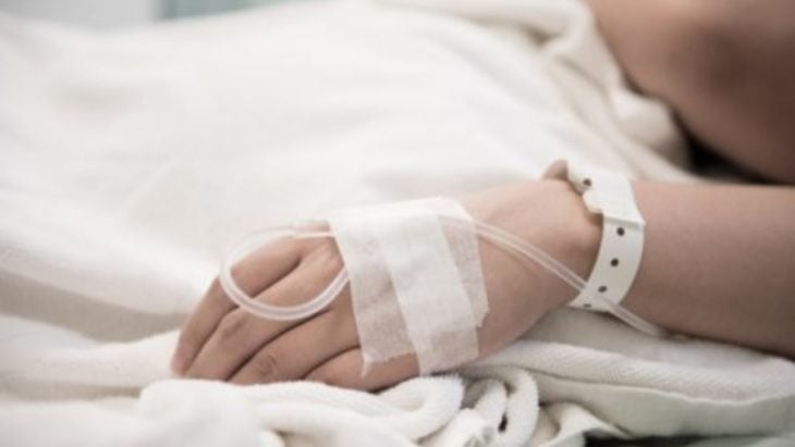 Mano de mujer con suero en cama de hospital