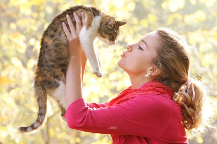 Mujer cargando a su gato y simulando que le dará un beso