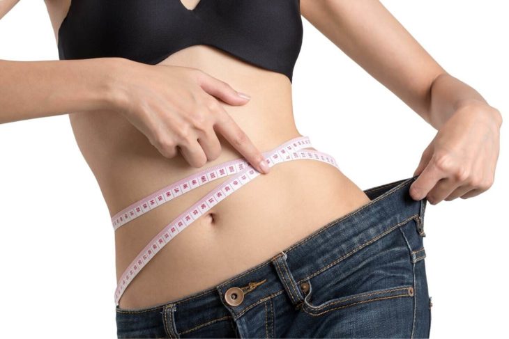 Mujer midiendo su cintura demostrando que perdió peso