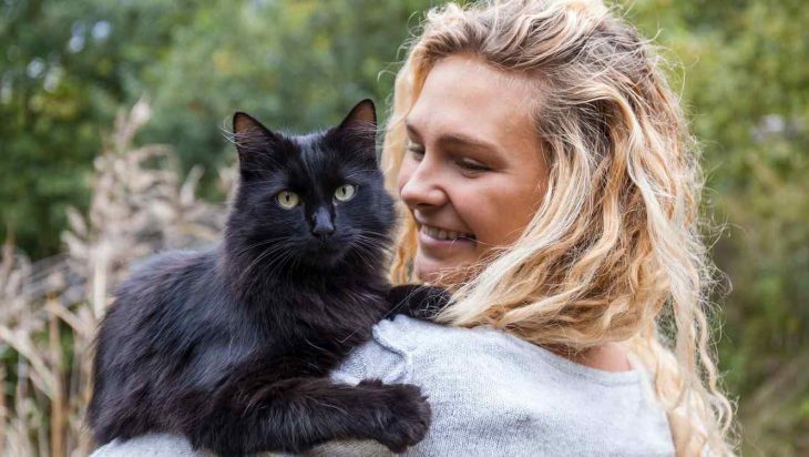 Donna bionda che trasporta un gatto nero