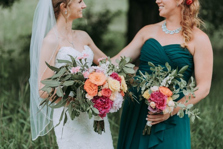 Novia y su dama de honor sosteniendo un ramo de rosas