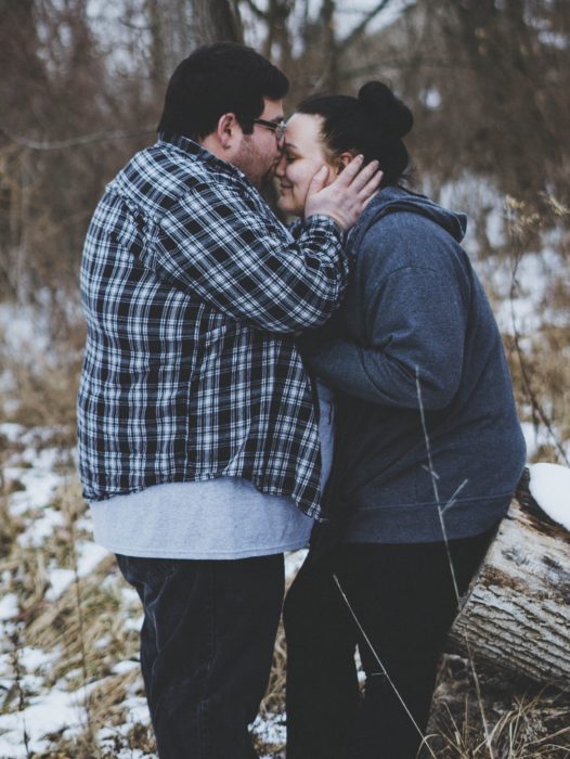 Hombre gordito dando beso en la frente a mujer