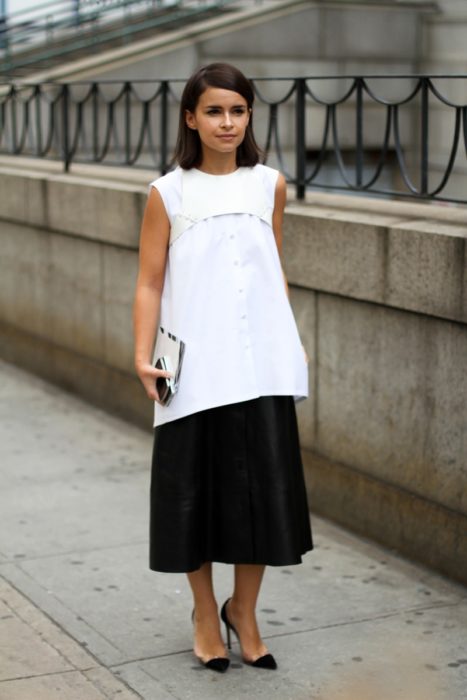 Una mujer vestida de falda larga negra y maxi blusa blanca con un arnés blanco encima