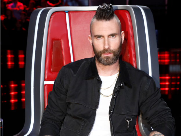 Adam Levine sentado en una silla roja en el programa The Voice