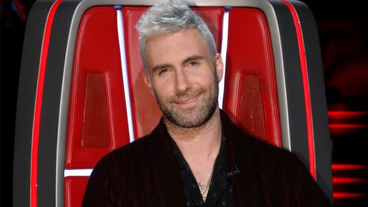 Adam Levine sentado en una silla roja en el programa The Voice