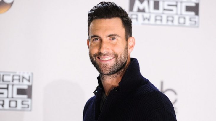 Adam Levine sonriendo en una alfombra roja