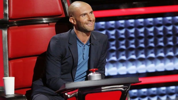 Adam Levine sentado en una silla roja en el programa The Voice