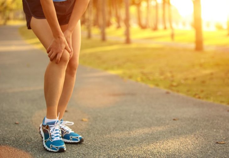 las piernas de una mujer con el fondo de un parque, ella se toca la rodilla en señal de dolor