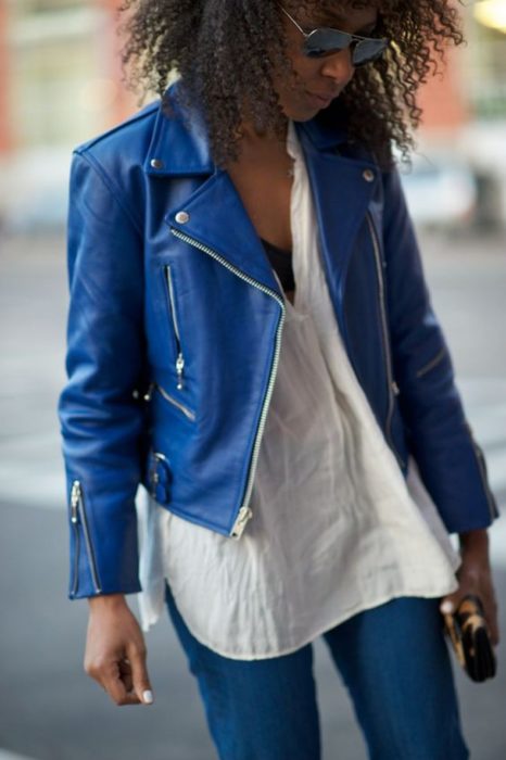 Chica morena de cabello afro con chaqueta de cuero azul rey