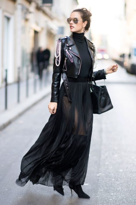 Mujer elegante con chaqueta de cuero con cadenas, falda de tul transparente y bolsa negra