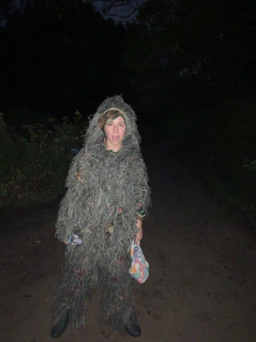 Chica caminando por un sendero disfrazada de arbusto