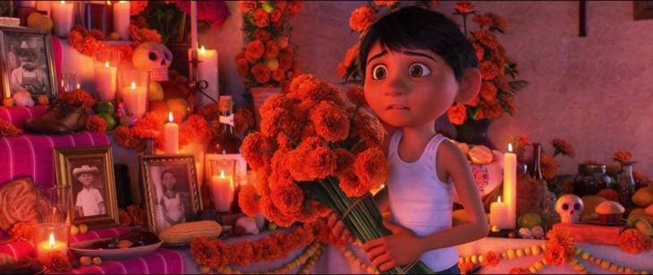 Escena de Coco, Pixar, Miguel dejando flores en el altar de muertos
