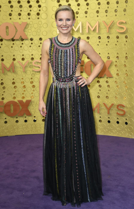 Kristen Bell posando en la alfombra roja de los premios emmy 2019 mientras usa un vestido negro con aplicaciones de colores 