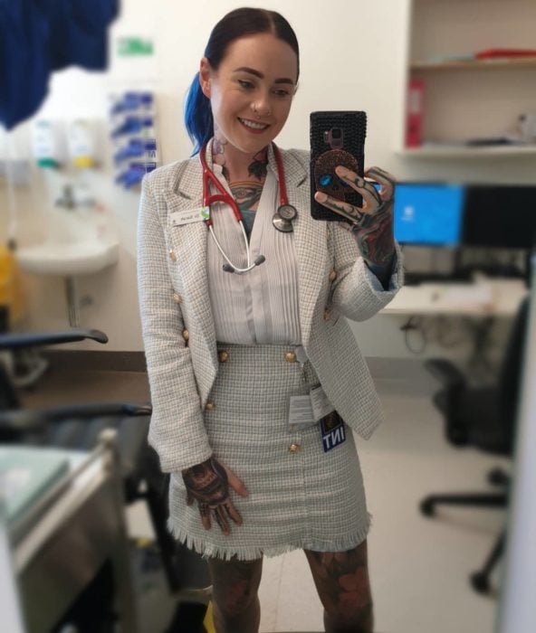 Sarah Gray con un traje color perla y su estetoscopio alrededor del cuello en una oficina de un hospital