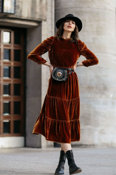 Ropa estilo boho o hippie chic; chica con manos en la cintura, con vestido midi de terciopelo con cangurera, con sombrero y botas militares negras