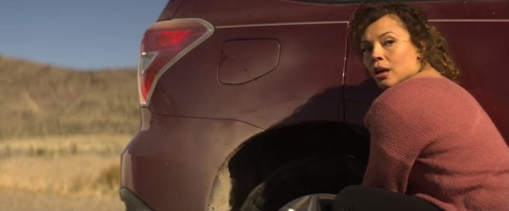Mujer cambiando el neumático de un automóvil, escena de la película Rattlesnake, Netflix
