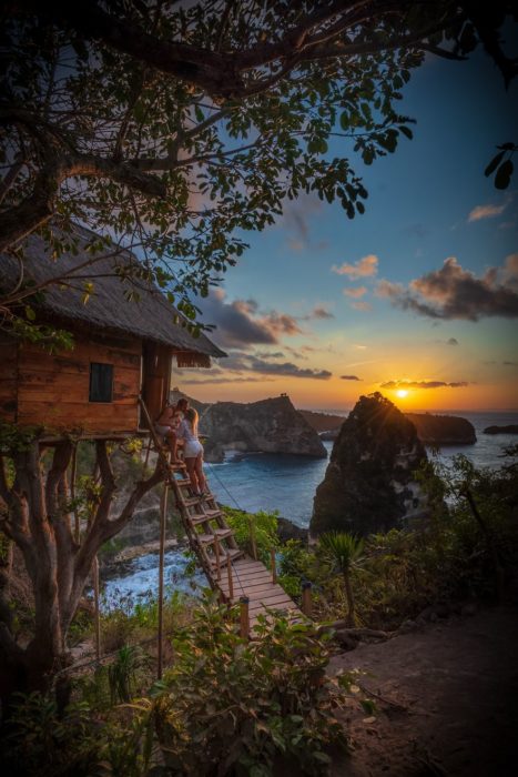 Parejas besandose al pie de las escaleras de una cabaña mientras ven el atardecer