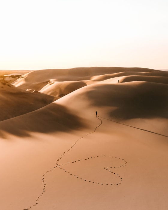 Persona caminando por el desierto y formando un corazón con sus pasos 