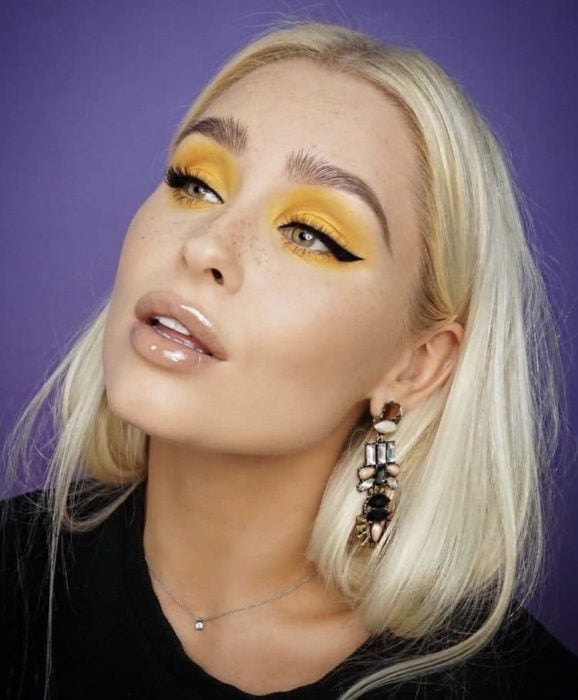 Chica usando un maquillaje monocromático en color amarillo con un delineado negro 
