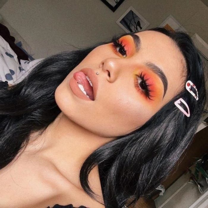 Chica usando un maquillaje estilo monocromático de colores naranja con pestañas y delineado 