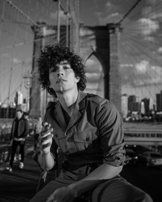 Jorge López Astorga, actor de serie de Netflix que interpreta a Valerio; fotografía en blanco y negro de chico de cabello chino y despeinado posando en un puente