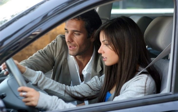 Mujer manejando y hombre hablando con ella