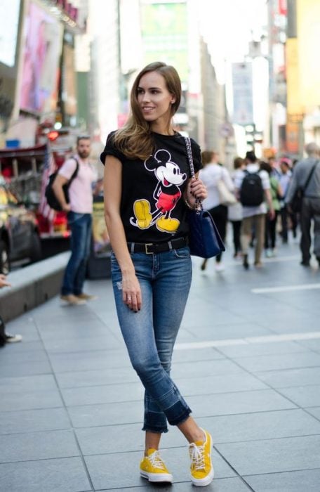 Chica paseando por las calle y modelando un outfit con camisa estampada de Mickey Mouse