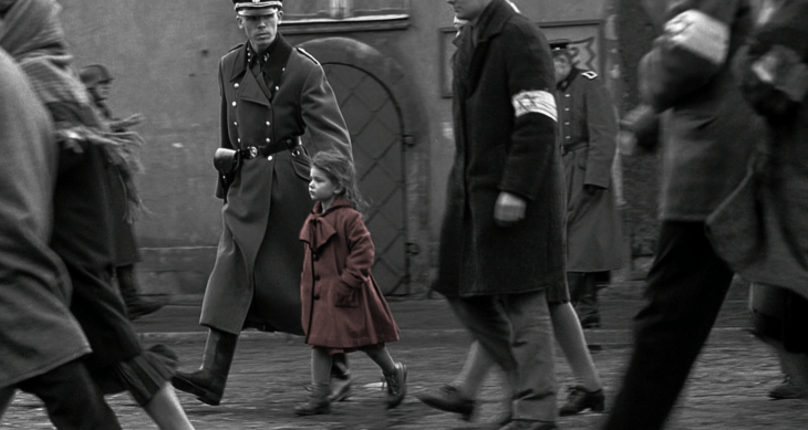 Escena de la película Schneider, niña con saco rojo caminando por las calles 